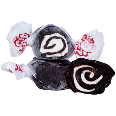 Three pieces of Black Licorice Salt Water Taffy – Freeze-Dried Classic with a Bold, Crunchy Twist, each wrapped in white wax paper with red print. One taffy is unwrapped, revealing its distinctive swirl pattern inside.